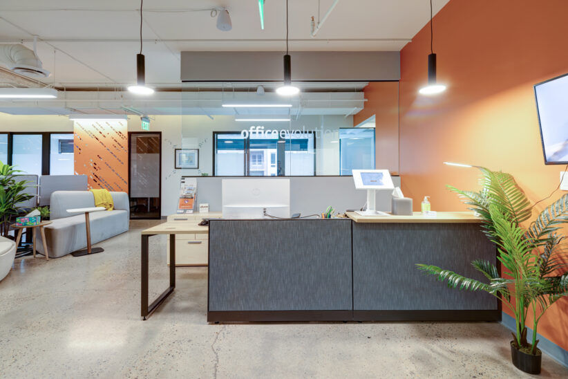 Beautiful front desk with natural greenery, natural light, TV display, and comfortable seating